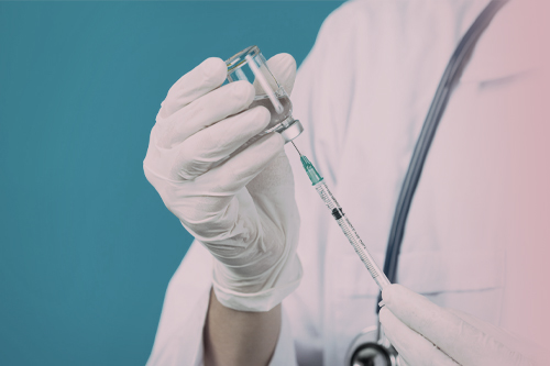 Врач набирает лекарство из ампулы в шприц